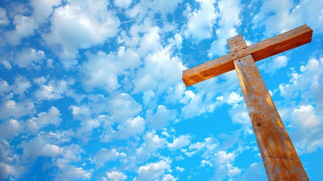 Wooden Christian cross reaching towards a blue sky, scattered clouds, upward perspective, symbolic of faith and spirituality, calm and reflective