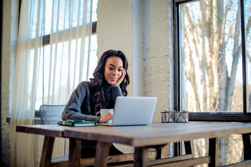 An african american woman sitting at the table and using her laptop