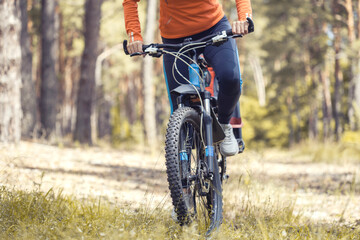 Naklejka premium woman cyclist rides in the forest on a mountain bike.