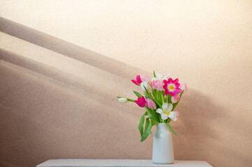 tulips in vase on table on background wall