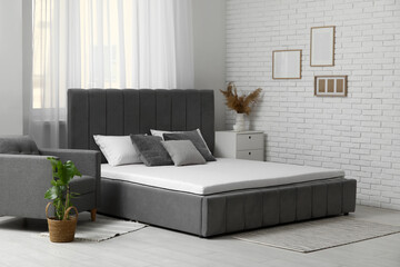 New orthopedic mattress on stylish bed in room