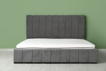 Obraz premium New orthopedic mattress on stylish bed near green wall in room