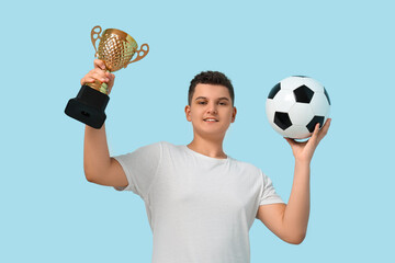 Teenage boy with soccer ball and gold cup on blue background