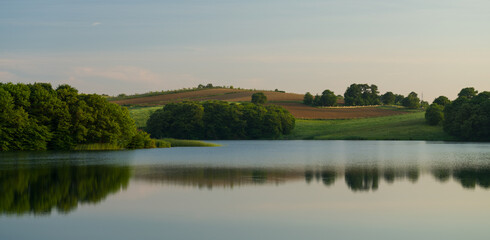 A tranquil lake and a panoramic view of the forest and fields around the lake in spring. High resolution nature background