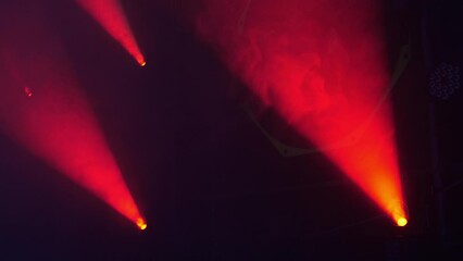 Close-up of the red beams of searchlights in the smoke at a concert or circus performance. Professional lighting equipment using smoke. Circus background.