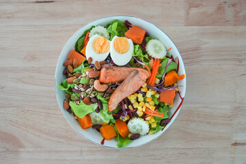 Grilled salmon salad on wooden background.