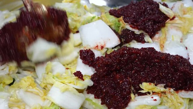 Freshly chopped Chinese cabbage in a bowl, being seasoned with a rich tomato sauce for convenient preparation.