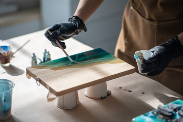 Precise neat female artist applies white pigment with stick, creates pattern of waves on epoxy...