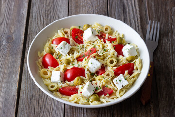 Orzo pasta with white cheese, tomatoes and olives. Healthy eating. Vegetarian food.