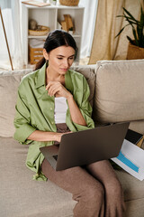 Casual woman on a couch, engrossed in laptop work.