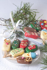 Christmas dessert. Sweet food. Cheesecake on a stick in the shape of ice cream. Children's treat in winter. Candy Christmas tree, snowman, deer and Santa Claus. Gingerbread cookies.