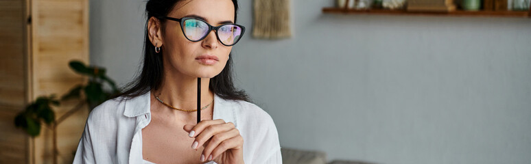A stylish woman with glasses confidently holds a pen.