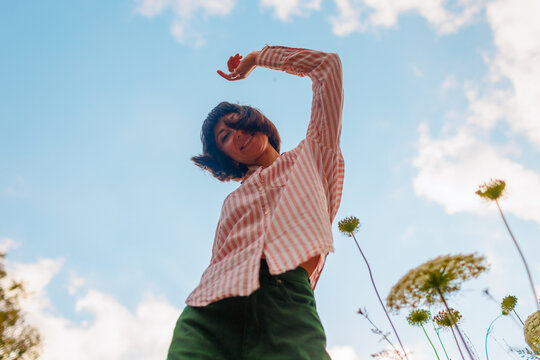 Photo of a girl dancing in a flower field against the sky.
