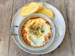 Pan-fried eggs, minced pork and buttered bread on a stainless steel plate.