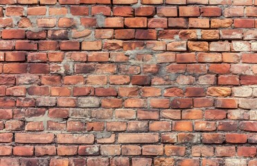 Fototapeta premium A close-up of an old brick wall with weathered and varied brick colors, showcasing the rustic texture and character. Ideal for backgrounds, architecture, and design themes.