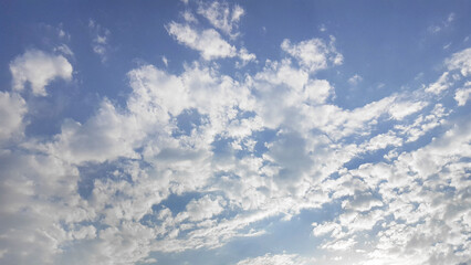 The azure sky, dotted with fluffy cumulus clouds, creates a picturesque natural landscape. The...
