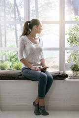 Young woman relaxing next to a window