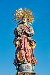 Fototapeta premium Die auf dem Marienbrunnen auf dem Marktplatz von Schwäbisch Gmünd thronende Figur der Mutter Christi, Maria Magdalena, mit Heiligenschein