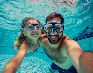 Fototapeta premium Father man and girl child daughter swimming underwater in water pool on summer vacation with plastique googles water action 