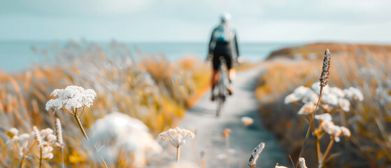 Cyclist riding on a scenic coastal path surrounded by wildflowers in bloom, capturing the beauty of summer and nature's tranquility.