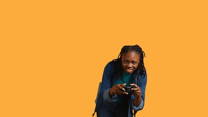 African american gamer holding controller, focused on finishing difficult videogame level. Woman gaming with gamepad, solving quests, isolated over studio backdrop, camera B