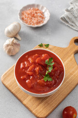 Canned whole peeled tomatoes with juice and parsley on table