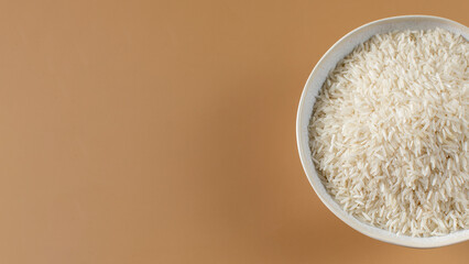 Bowl of aromatic basmati rice on light brown background