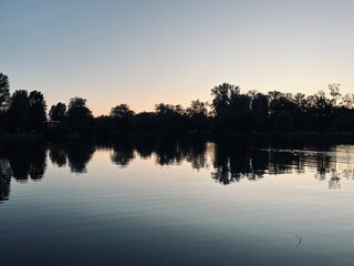 purple sky reflection on the lake surface, trees silhouettes reflection, twilights lake in the park