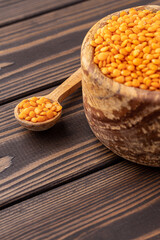 Photo of red lentils in wooden bowl with wooden measuring cup on wooden background.  Healthy lifestyle. Vegetarian and vegan diet.