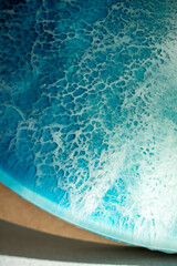 Closeup of azure blue epoxy resin sea painting artwork. Image of ocean on canvas, surface of water with foam, waves expressed in technique of fluid liquid art. Amazing artful pattern, masterpiece.