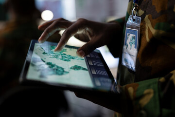 Army operations IT professional monitors satellite world map to search for enemy vessels or...