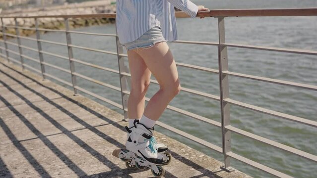 Close-up of a person rollerblading on a waterfront boardwalk on a sunny day, enjoying outdoor activities and fitness.