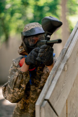 Fototapeta premium close up in the wild near tree structures player in a pintball uniform holds a pistol with a red balloon team game camouflage clothing
