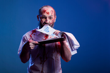 Portrait of mindless accountant worked to death, doing paperwork, biting files. Man working like...