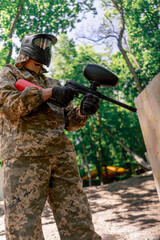 Naklejka premium in the wild near tree structures player in a pintball uniform holds a pistol with a red balloon team game camouflage clothing