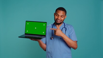 Portrait of practitioner showing medical instructions video on green screen laptop. Healthcare...