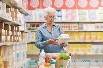 Senior woman reading information on a product package at the supermarket