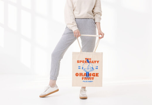 Woman model holding  a color customizable tote bag mockup faceless