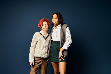 Young multicultural friends, stand together in stylish attire on a dark blue background.