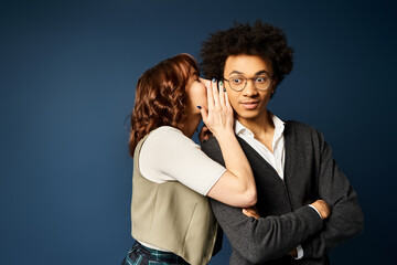 A young multicultural duo standing united in stylish attire against a dark blue backdrop.