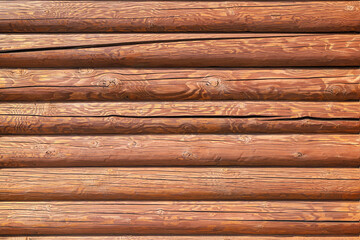 Texture of a log wall on a sunny day. A heavily cracked wall of a blockhouse as a background