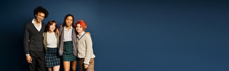 A diverse group of young friends, including a nonbinary individual, stand together in stylish attire on a dark blue background.