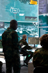 Fototapeta premium Special operations engineer examining surveillance CCTV footage to gather crucial information for a new mission, working on reconnaissance in general headquarters. Army conscripts in command post.