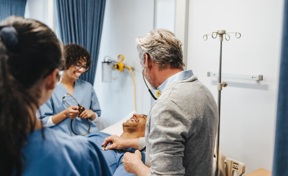 Senior doctor showing his students how to use a stethoscope in a hospital