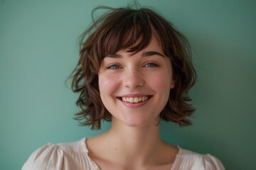 Portrait of a content caucasian woman in her 20s smiling at the camera in soft green background