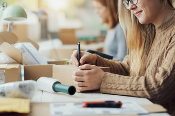 E-commerce employee writing a shipping address on a box