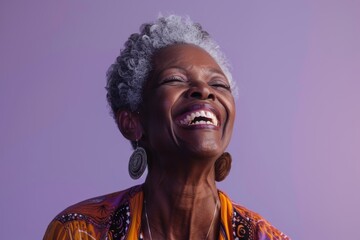 Obraz premium Portrait of a blissful afro-american woman in her 60s laughing isolated in soft purple background