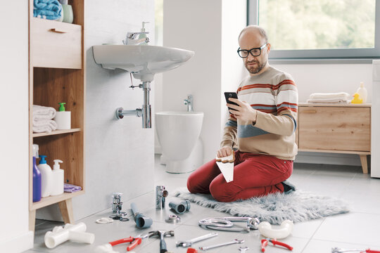 Confused man searching online how to repair a sink