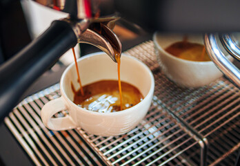 Close-up of espresso pouring from the coffee machine into a coffee cup. Professional coffee brewing