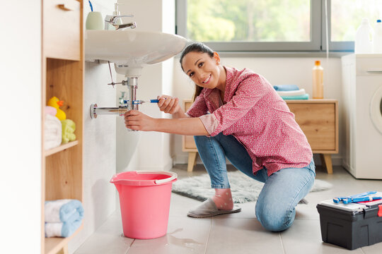 Skilled woman repairing a leaky sink by herself